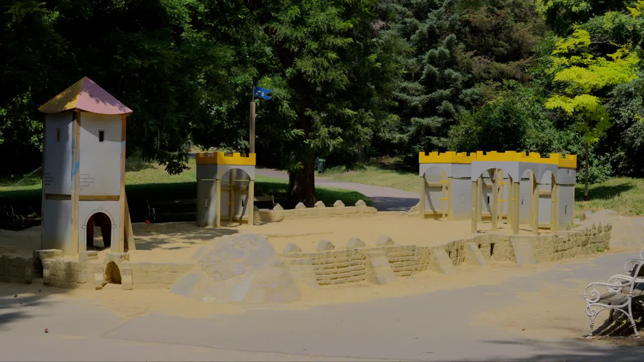 Children's playground with a sand and castle at T&uuml;rkenschanzpark in Vienna during a sunny day at noon in slow motion