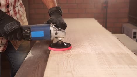 el hombre lijando una tabla de madera con una lijadora eléctrica