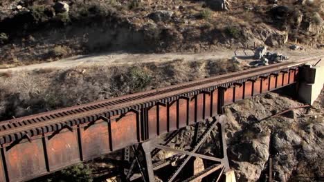 un helicóptero sobrevuela las vías del tren en un puente que conduce a un túnel