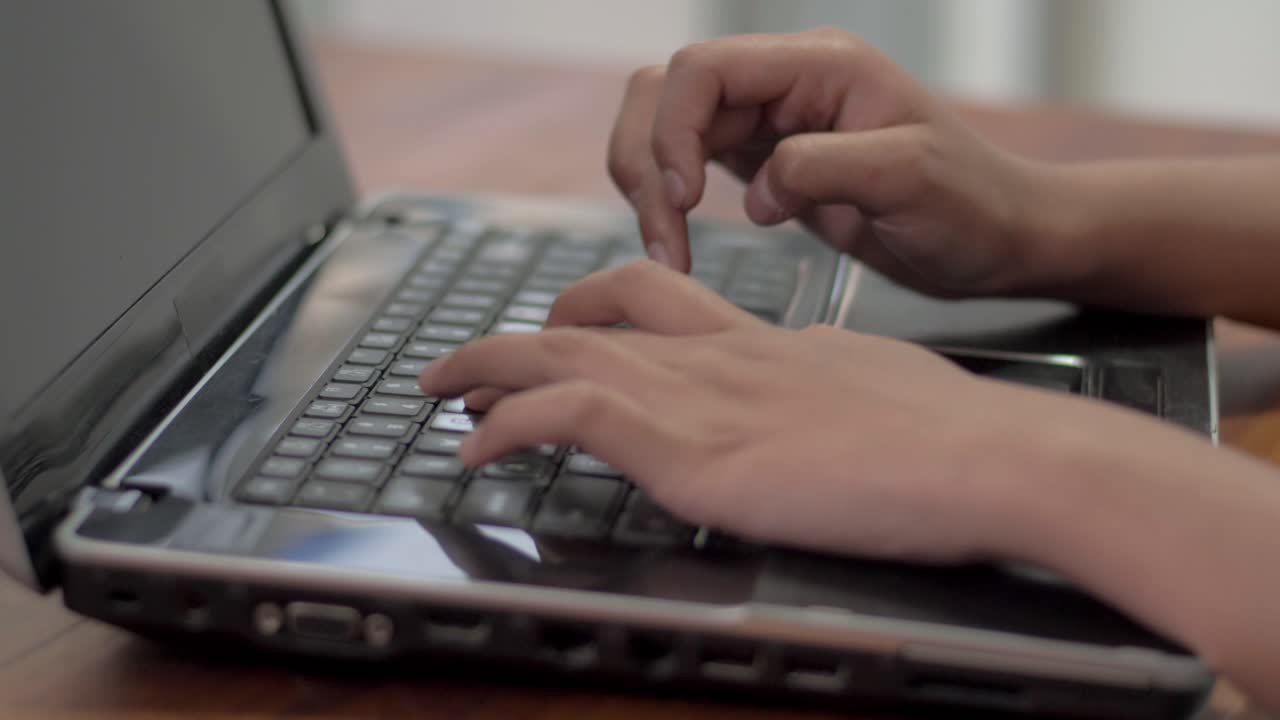 Close-up of a girl's hands typing swiftly on the laptop, demonstrating efficiency and productivity in her digital work