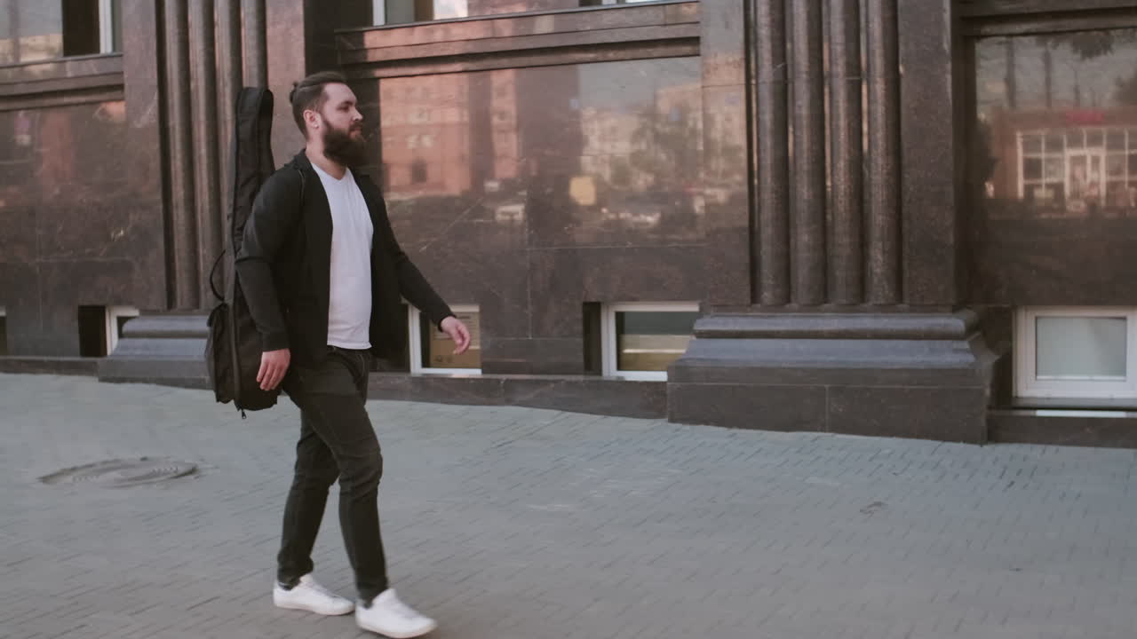 Musician Walking along Sidewalk in City