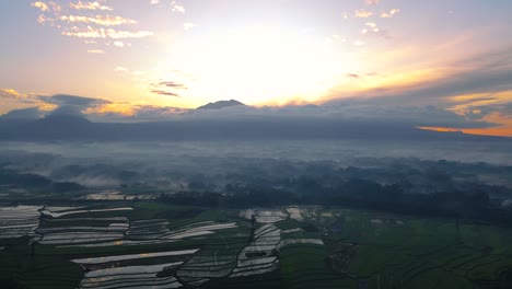 aerial view of rural landscape with mountain range on the background in sunrise time