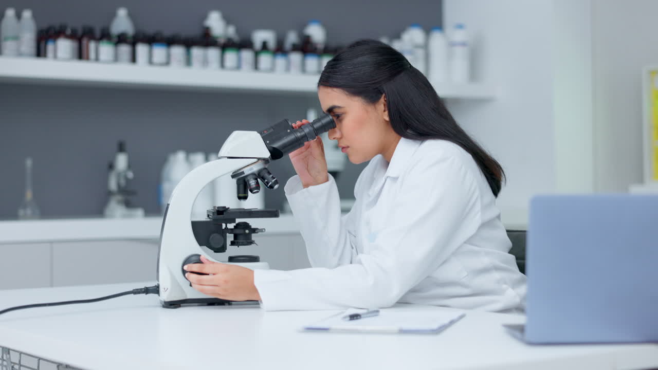 Laboratory scientist using a microscope to examine