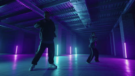 Two-Professional-skill-dancers-woman-and-man-enjoying-hip-hop-moves-performing-freestyle-dance-together-in-an-abandoned-building.-Caucasian-band-make-modern-freestyle-dance-indoors.