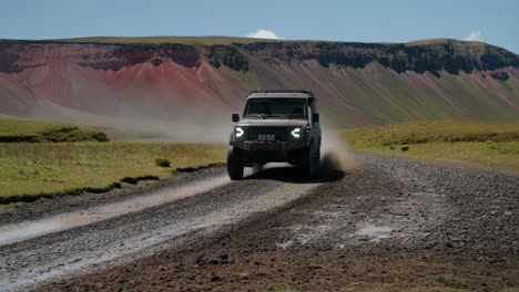 off-road 4x4 vehicle driving on a muddy track through a rugged mountain landscape