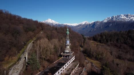 Minaret-at-Consonno-ghost-town,-aerial-establisher-view,-sunny-winter-day