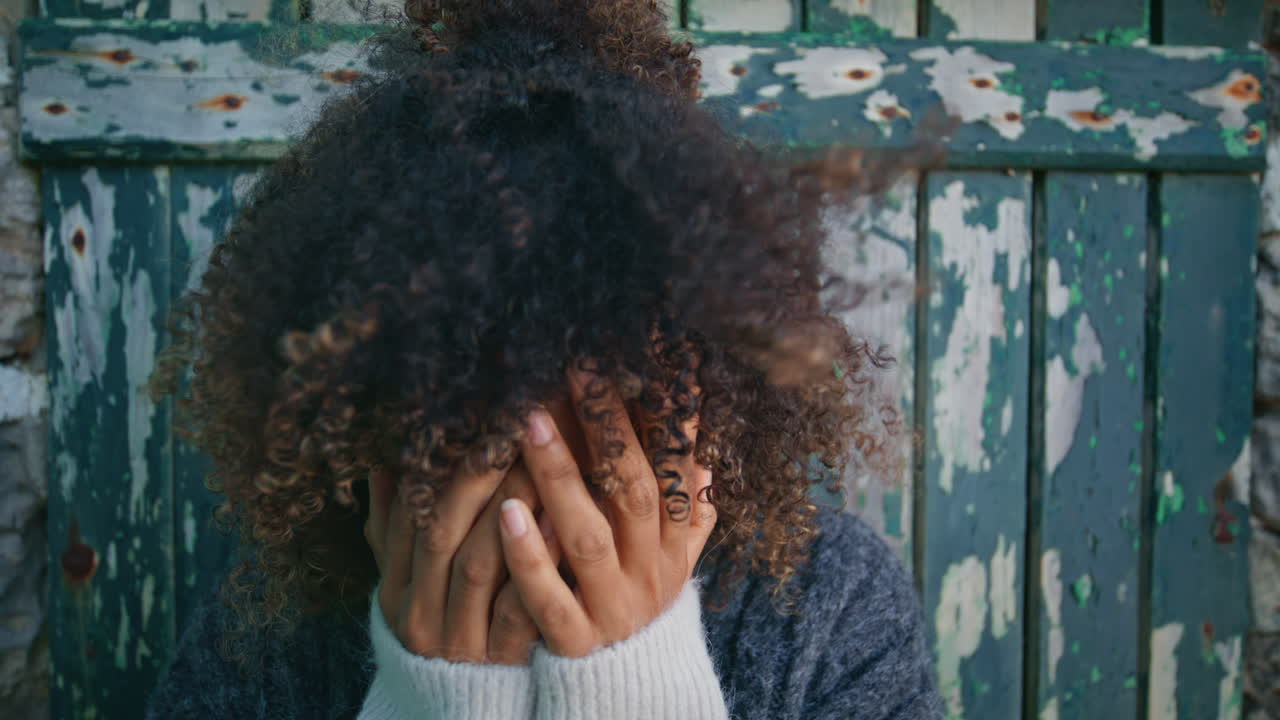 Upset woman standing vintage door at windy nature closeup. Depressed lady crying