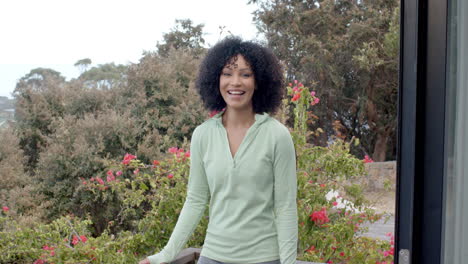 biracial woman smiling in garden with vibrant flowers, copy space