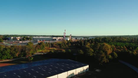 aerial view of macon, georgia showing a large warehouse amidst lush autumnal trees under a clear sky