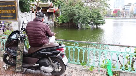 man fishing from scooter by lake