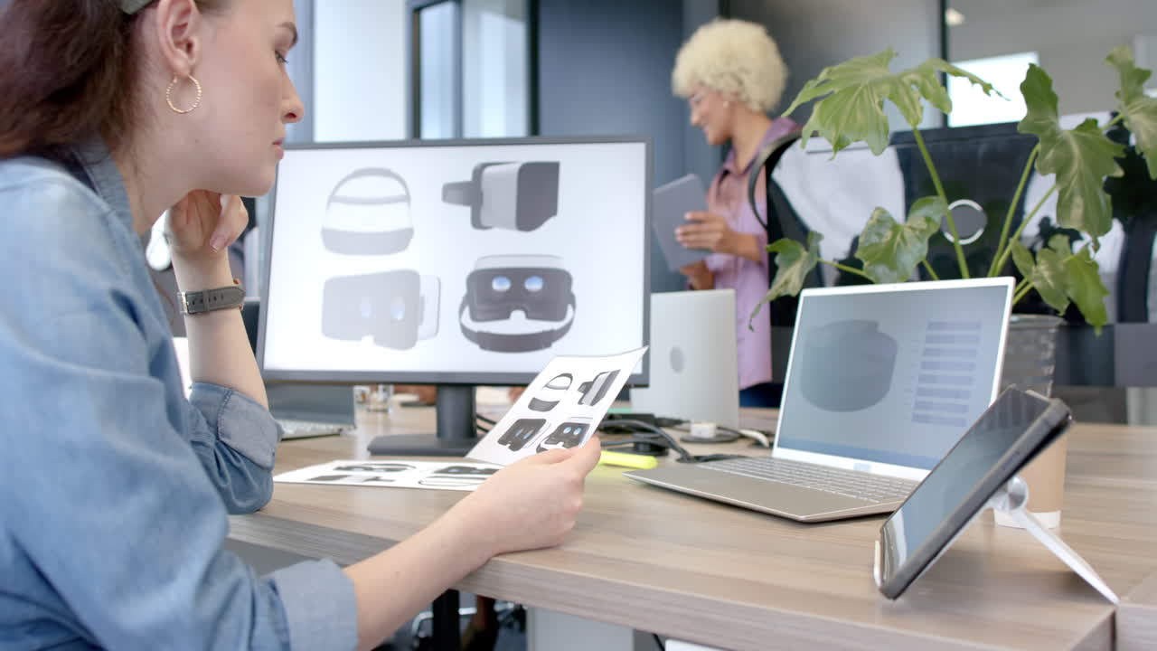 Designing VR headsets, woman reviewing sketches at modern office desk
