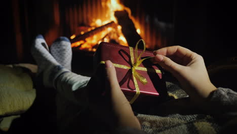 Woman-Holds-A-Box-With-A-Gift-In-Her-Hands-Sits-Near-The-Fireplace