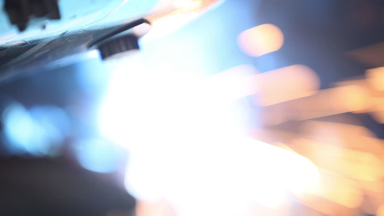 hermosas chispas de bokeh que vuelan alrededor de la máscara de soldador mientras fabrican láminas de metal juntas