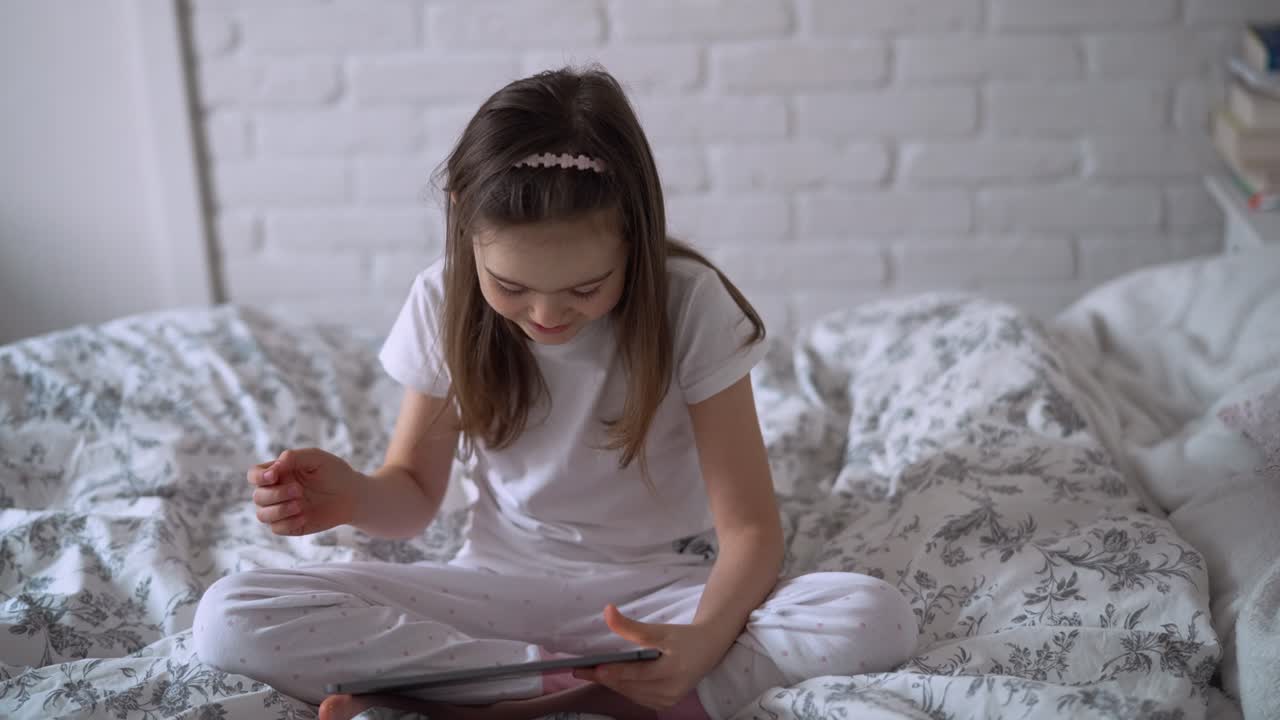 chica usando la tableta en la cama