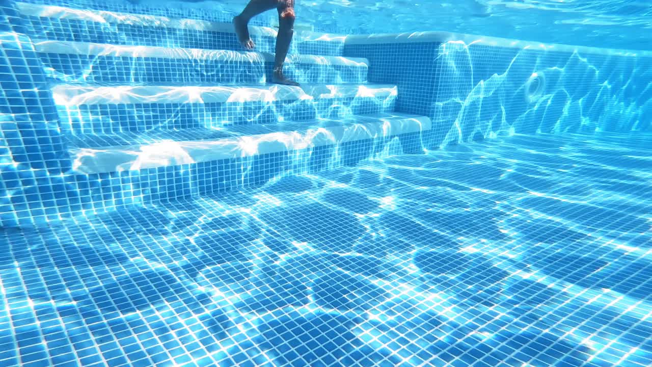Glad dreng svømmer under vandet i poolen. Undervandsvideo.