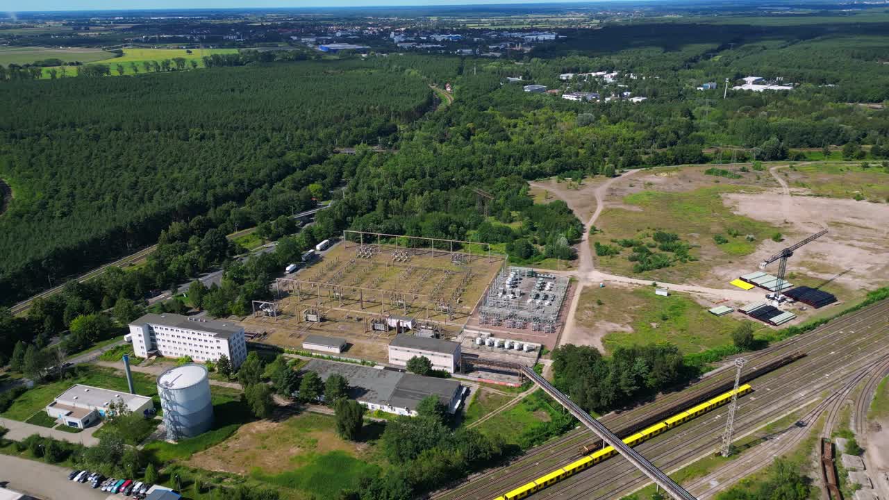 Hennigsdorf substation, distributing electricity and surrounded by a lush green forest in Brandenburg, Germany. Best aerial view flight wide orbit overview drone