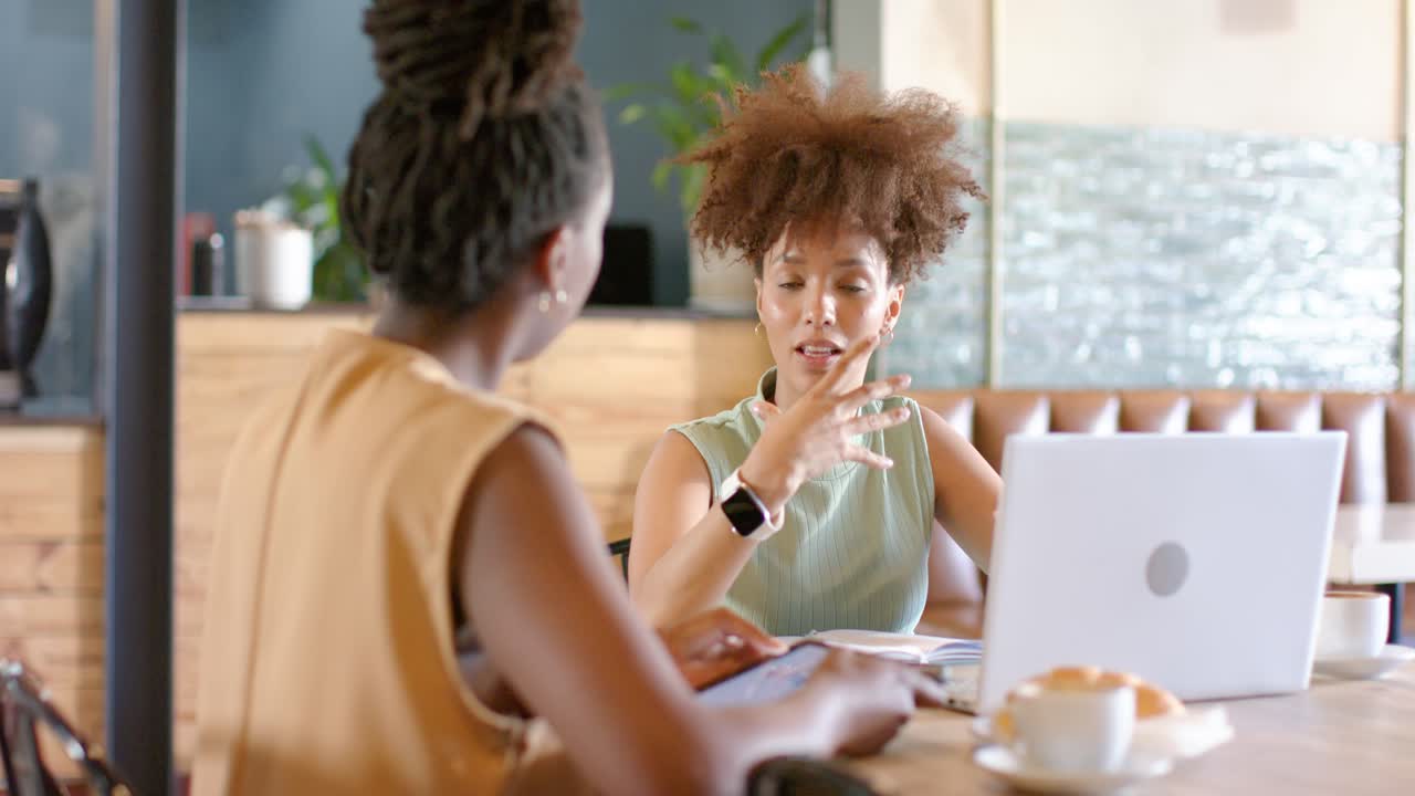 African American women team starting planning at cafe, gesturing, tapping tablet, checking laptop