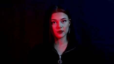 Young,-serious-and-beautiful-female-model-sitting-in-front-of-a-black-background-lit-by-red-light