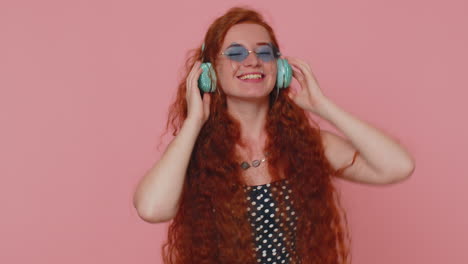 Young-redhead-woman-in-dress-listening-music-on-headphones,-dancing-disco-fooling-around-having-fun