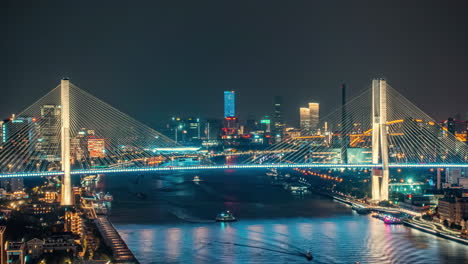 vibrant night view of a city skyline with an illuminated bridge and boats on the river in shanghai