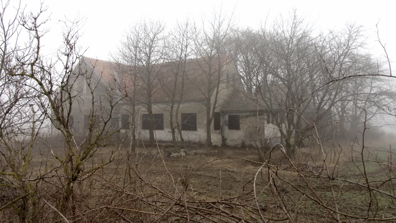Casa inquietante si erge nella nebbia, ripresa con un lento movimento di dolly.
