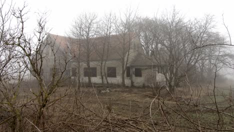 creepy house stands in the mist, shot with slow dolly movement.