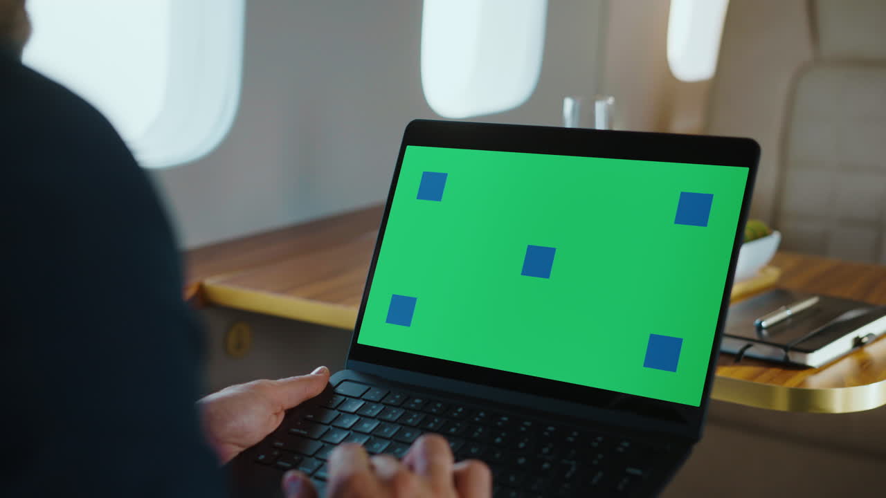 Man Working on Laptop with Green Screen on Airplane