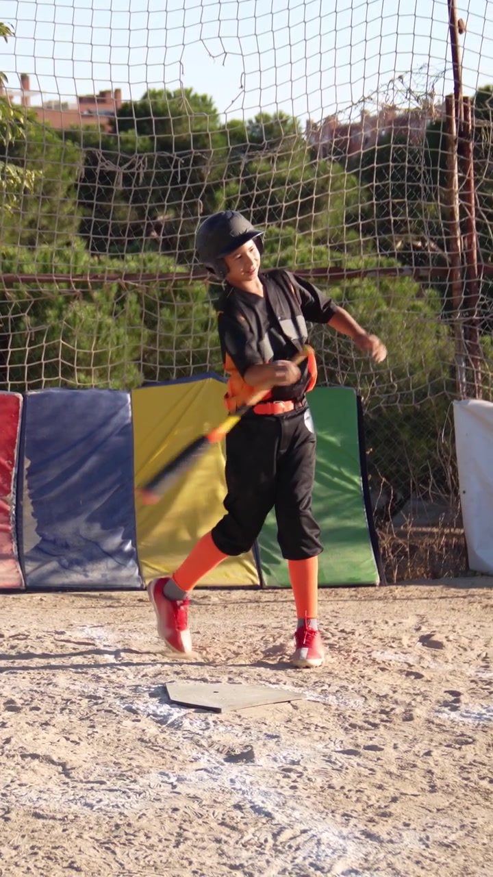 Jovem jogador de beisebol praticando o swing do bastão no home plate.