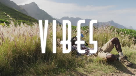 animation of the word vibes written in white over man hiking in mountains lying in tall grass