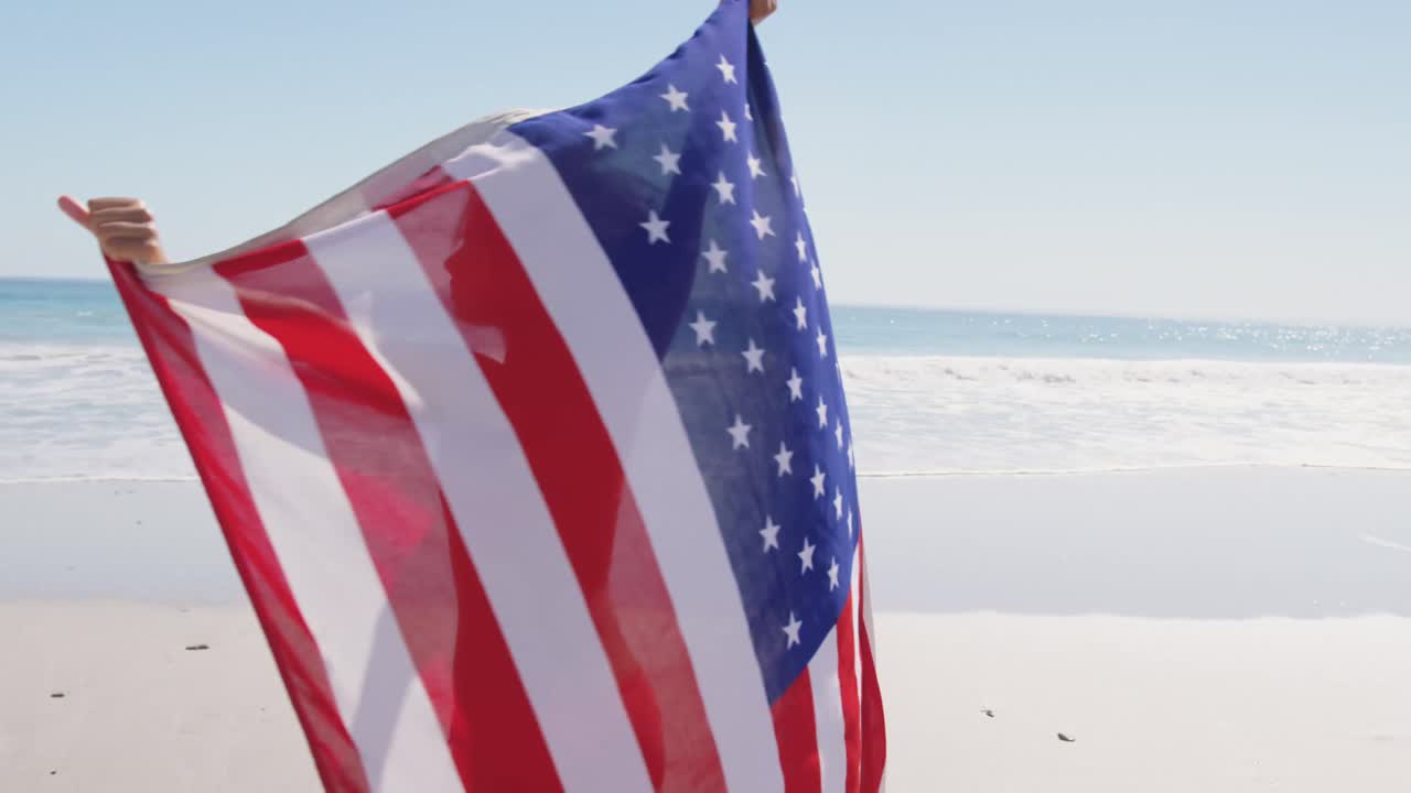 mujer joven bailando con bandera en la playa 4k