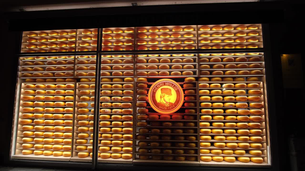 Inside the glass window, round cheeses serve as décor, with the company logo displayed at the center, in Munich, Germany.