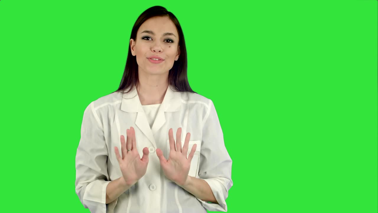Giovane donna sorridente in camice da laboratorio che parla alla telecamera su schermo verde, Chroma Key.