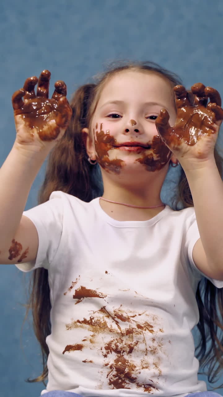 Portrait of girl with chocolate. Small girl with chocolate smeared all over her face and fingers. Vertical video