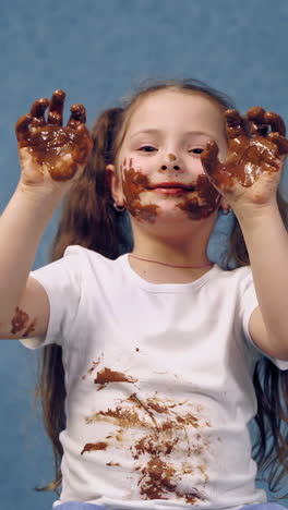 portrait of girl with chocolate. small girl with chocolate smeared all over her face and fingers. vertical video
