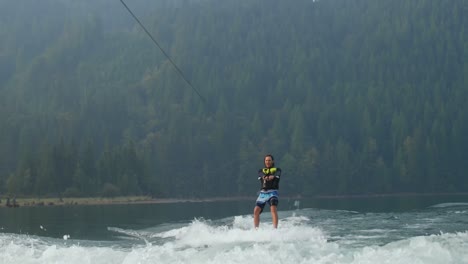 Vista-Frontal-De-Un-Joven-Caucásico-Haciendo-Trucos-En-Wakeboard-En-El-Río-De-La-Ciudad-4k