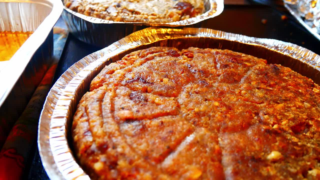 Urval av vegetarisk och traditionell korvfyllning i aluminiumformar på köksbänken, kameraåktning vänster.