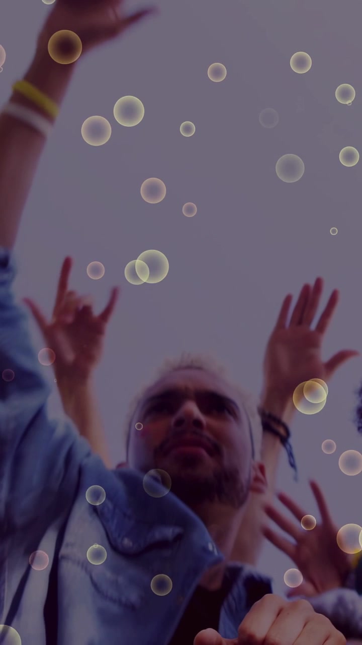 Vertical video: Denim-clad man raising arm, leading peers reaching sky, bubble overlay boosting ads