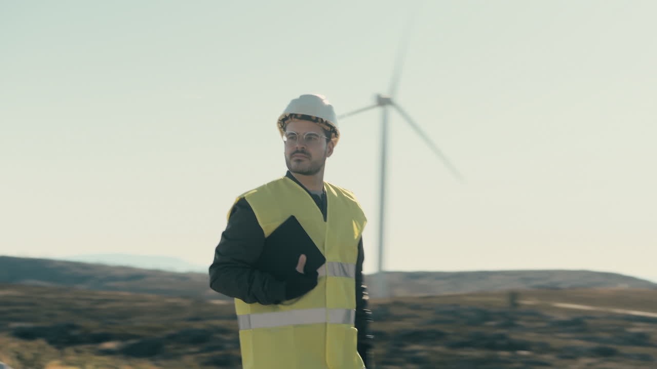 A renewable energy engineer in reflective gear checks wind turbines while walking in a field of renewable energy generators, emphasizing the importance of maintenance for a sustainable energy future