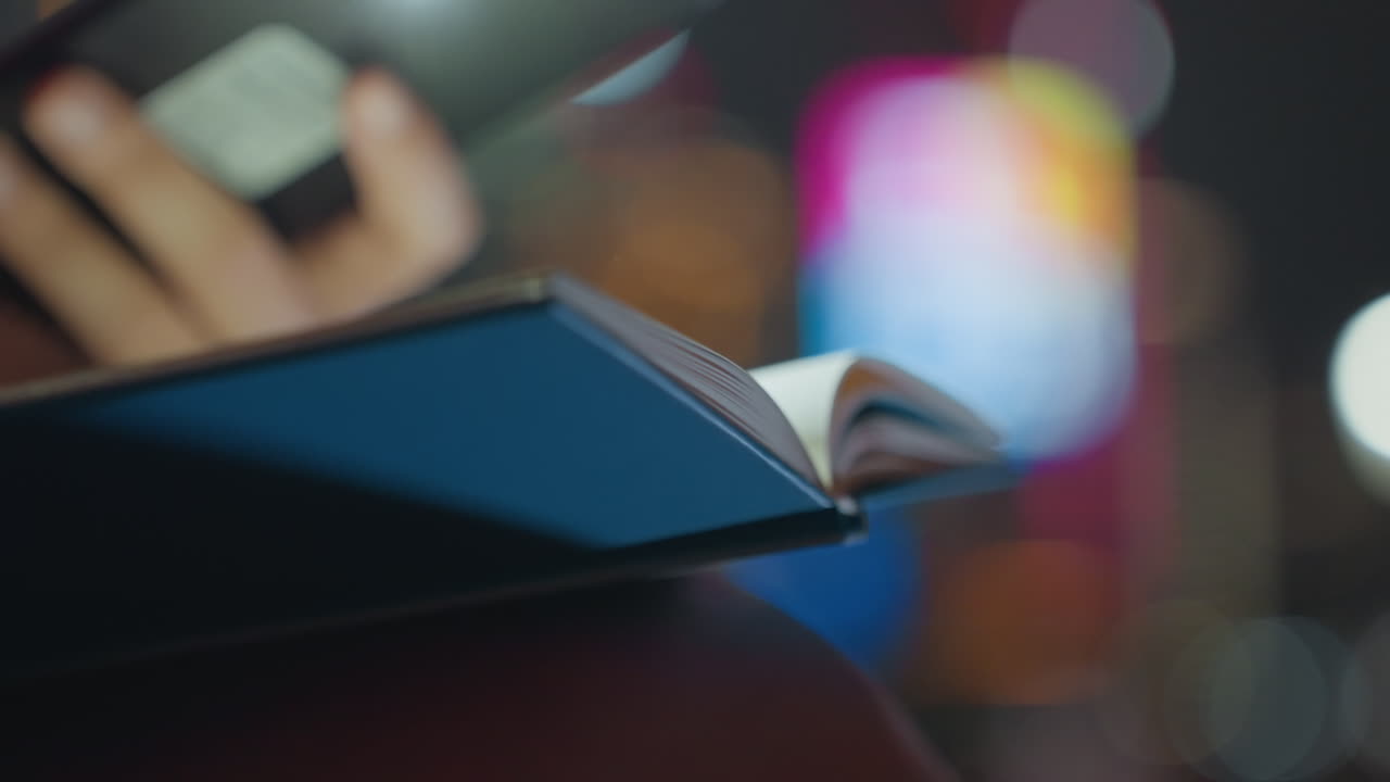Phone light illuminating open book, urban commuter studies late at night with neon bokeh and fingertip marking pages, quiet concentration and app notifications glowing, focused revision in city