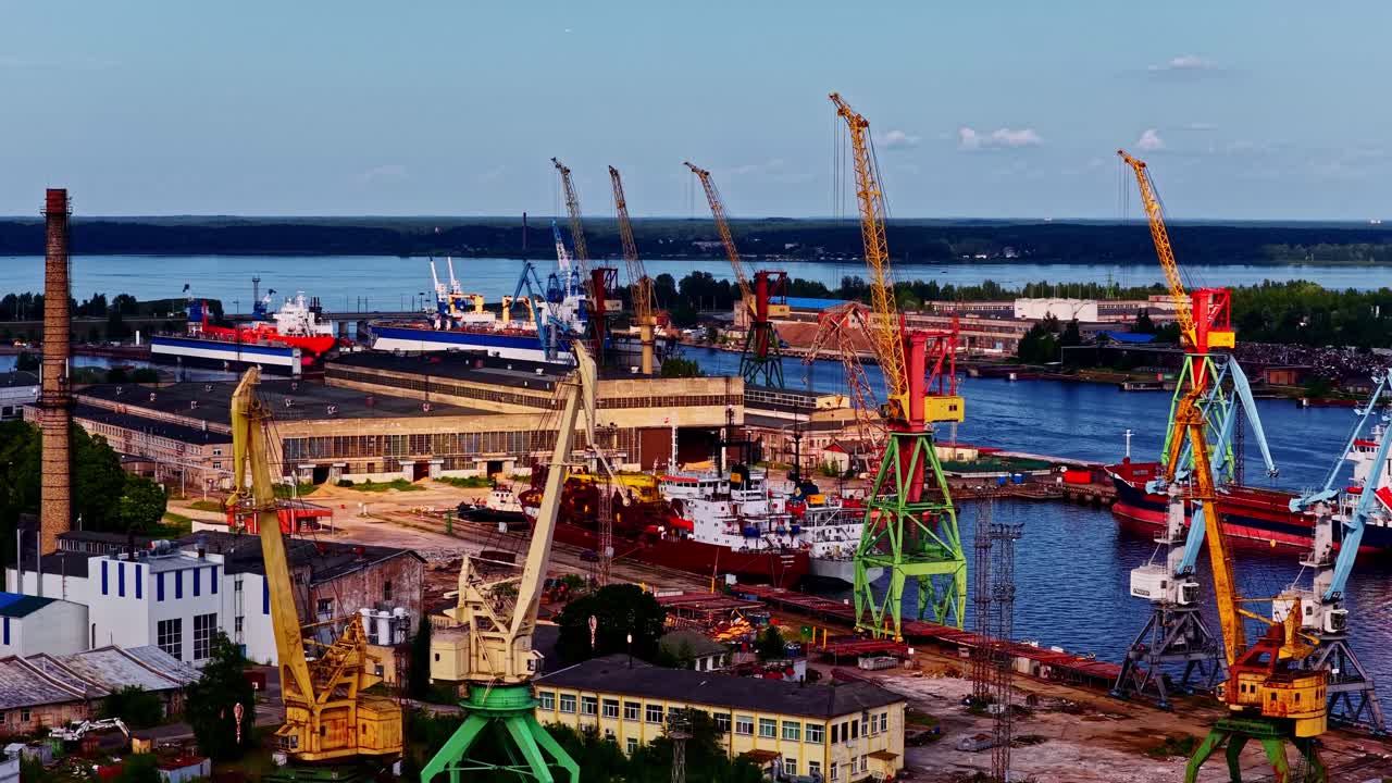 Riga, Latvia Baltic Sea Port terminal on the Daugava River with cranes for loading and unloading shipping containers - sliding aerial reveal