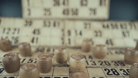 Macro-video-of-a-Bingo-board,-studio-lights,-120-fps,-slow-motion,-wooden-chip-digits,-Raw-footage,-lottery-desk-game,-card-numbers,-crane-pull-back-movement