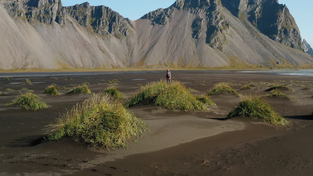 스토크스네스의 풍경의 전설적인 드론 풍경. 웨스트라호른 산을 바라보는 모래 언덕에 있는 여성 관광객. 아이슬란드 자연.