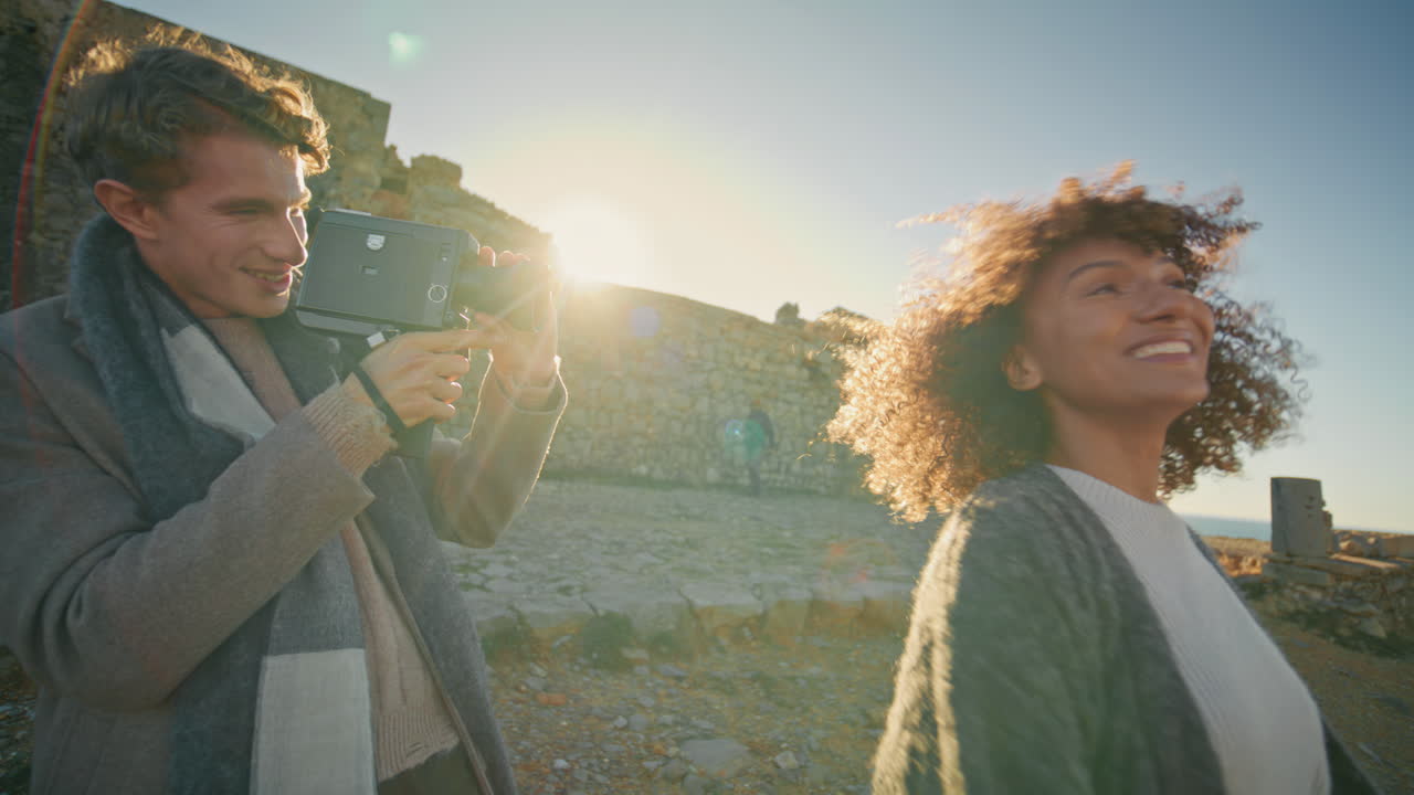 Male photographer photographing woman at sunset shore closeup. Girl laughing