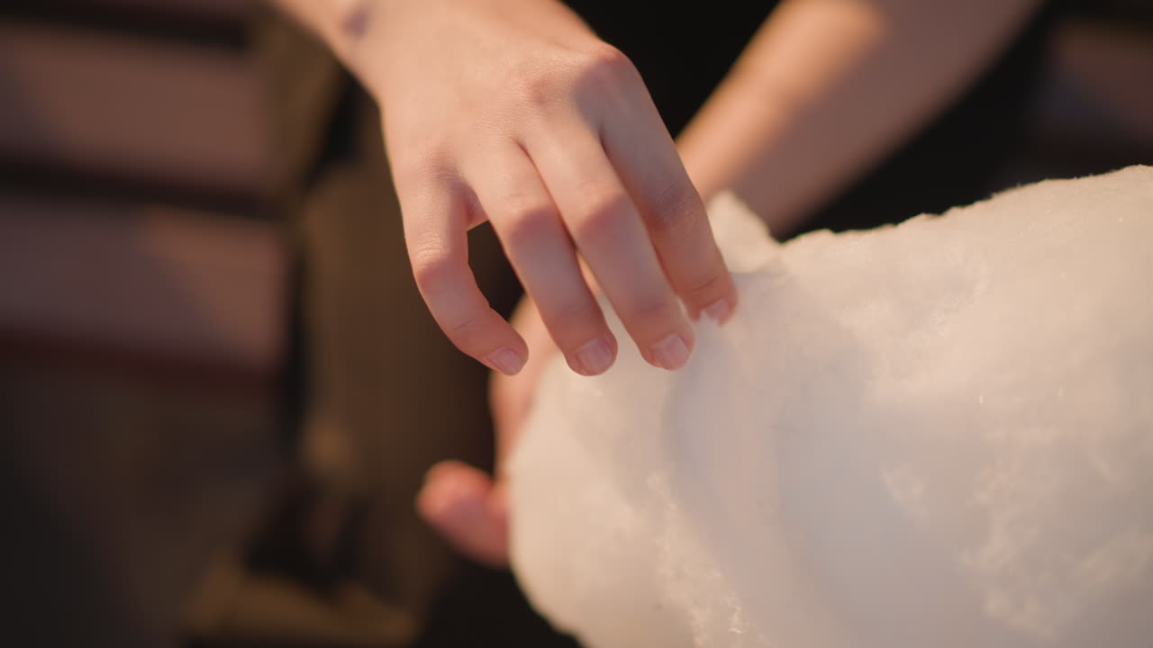 evening street hands pulling cotton candy, closeup on fingers shaping fluffy sugar cloud with warm bokeh lights, vendor apprentice crafting delicate strands, soft tactile motion, moody market