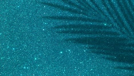 shadows from a palm tree on a blue glitter sparkling shining background. minimal art, glamor, vacation, summer, party concept.