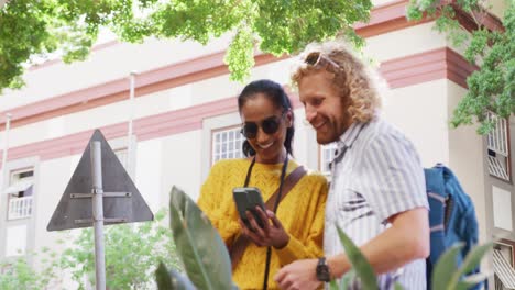 una pareja feliz con equipaje usando un teléfono inteligente en la ciudad.