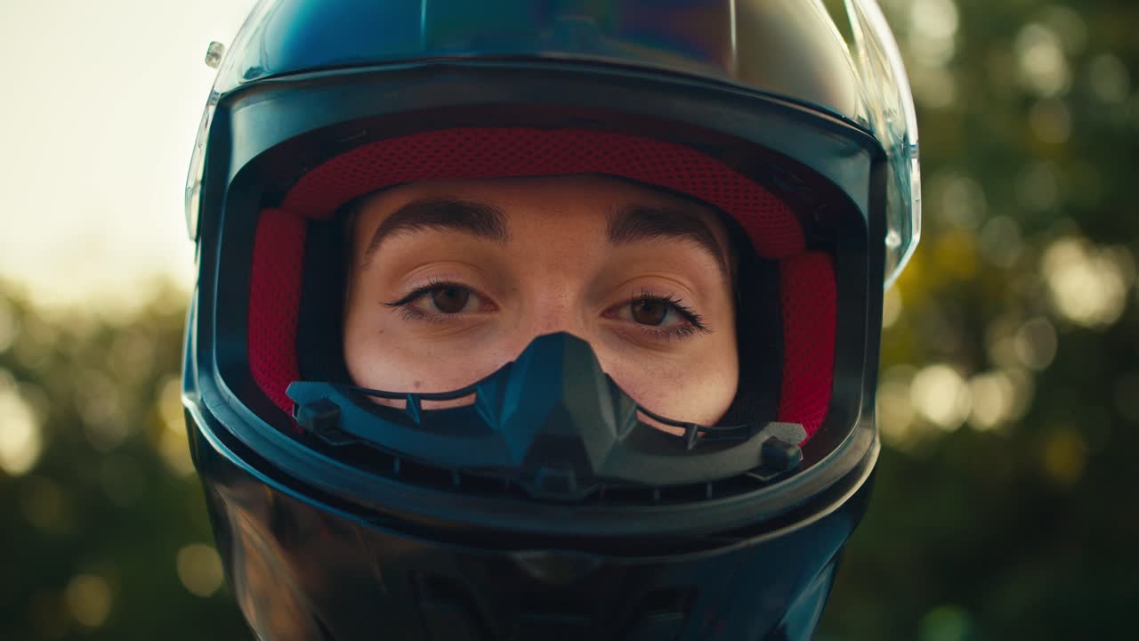 Close-up shot of a girl opening the protection of a motorcyclist's helmet and looking at the camera