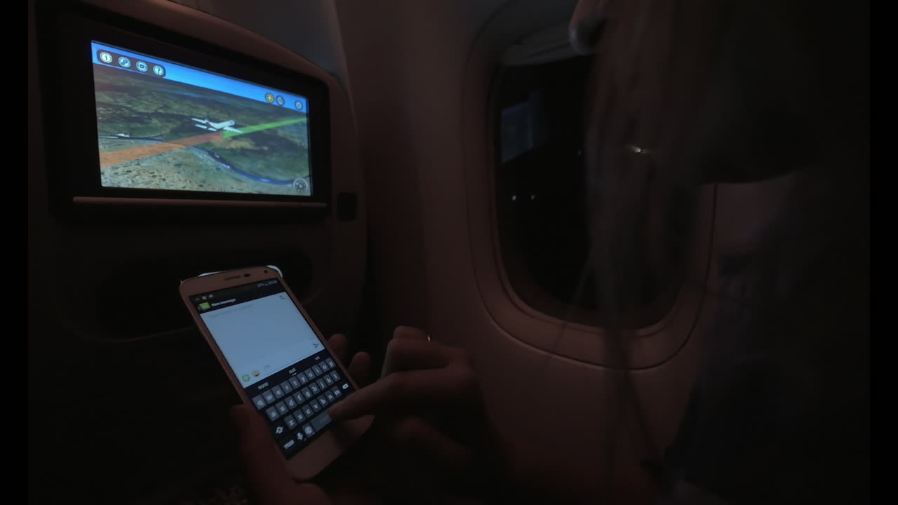 mujer escribiendo mensajes de texto durante un vuelo nocturno