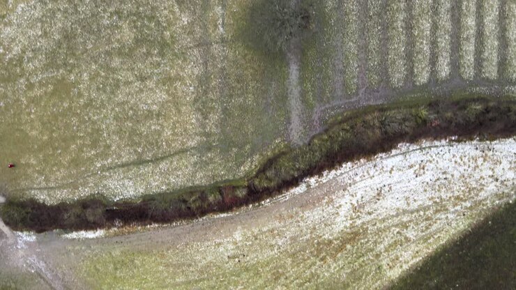 A top down aerial drone view flying over froze, muddy winter fields
