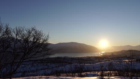 video of a snowy winter landscape with a sunrise-sunset over the city of tromsø, norway